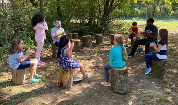 School age children sitting in circle outside